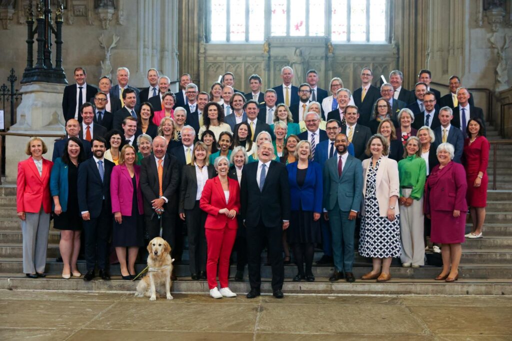 Photo of the 72 Lib Dem MPs in Parliament, with Jennie the guide-dog near the front.